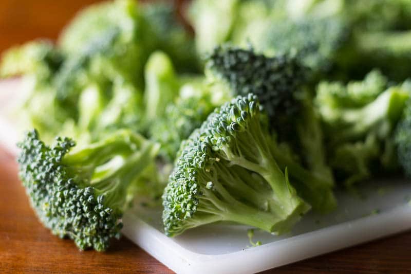 Raw broccoli on a white plastic cutting board