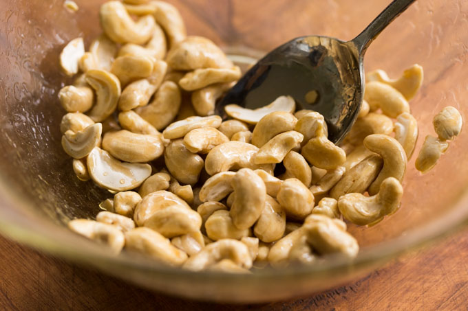 Cashews stirred in a bowl with maple syrup and salt