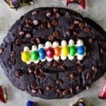 Made with chocolate chocolate chip cookie dough, vanilla frosting, and M&M's, this fun football cookie cake is very easy to make and perfect for parties.