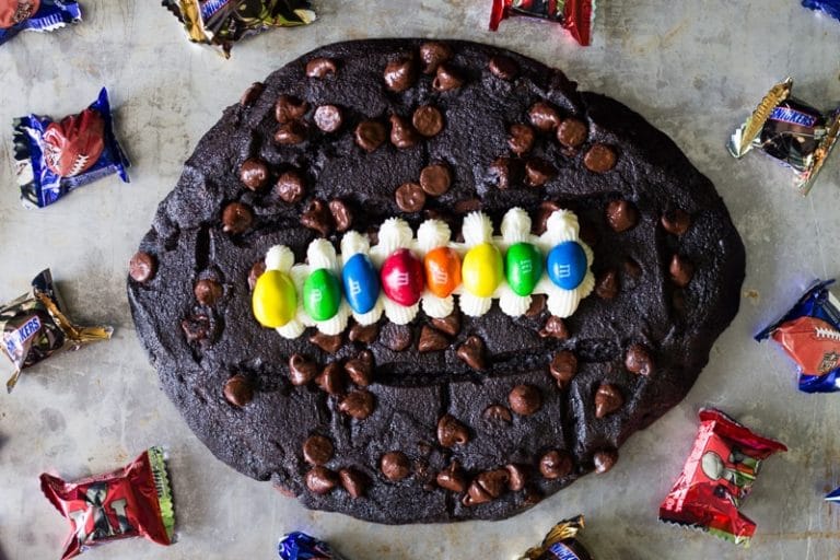 Made with chocolate chocolate chip cookie dough, vanilla frosting, and M&M's, this fun football cookie cake is very easy to make and perfect for parties.