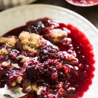 White plate of blackberry crumble with lots of juice