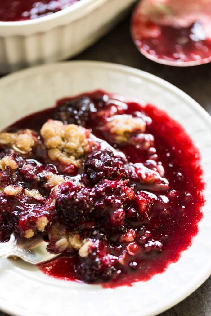 White plate of blackberry crumble with lots of juice