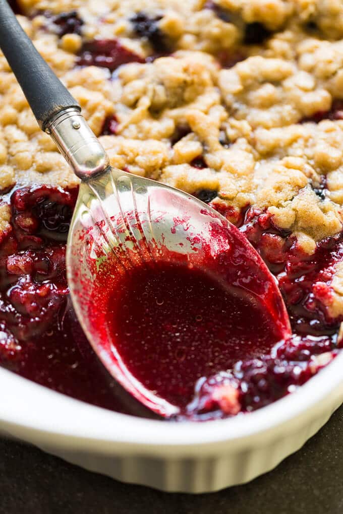 Vintage serving spoon in juicy blackberry crumble in a casserole dish