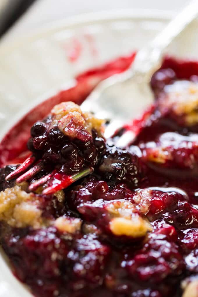 Blackberry crumble on a white plate with a silver fork