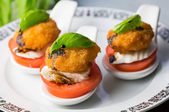 Crunchy Shrimp Caprese Salad Bites with Basil on a white plate with a black border