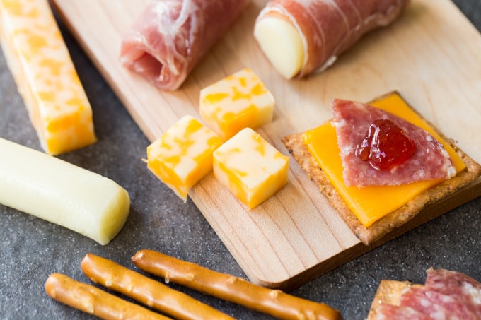 Closeup of kid friendly charcuterie board with meat, cheese, pretzels, and jam