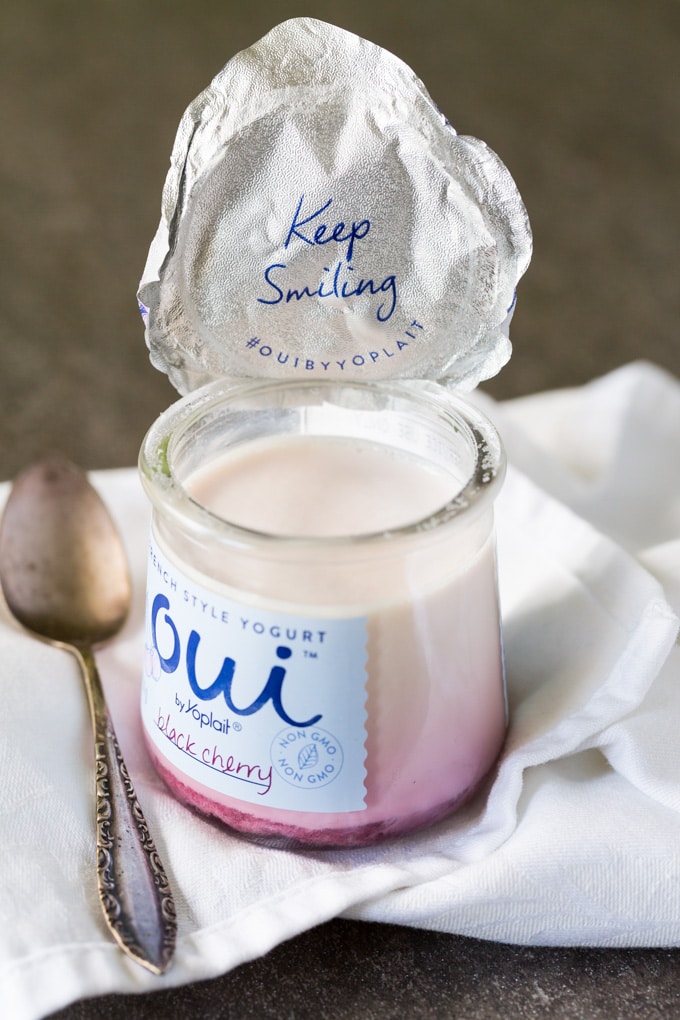 Open container of French yogurt in strawberry flavor with a spoon and napkin
