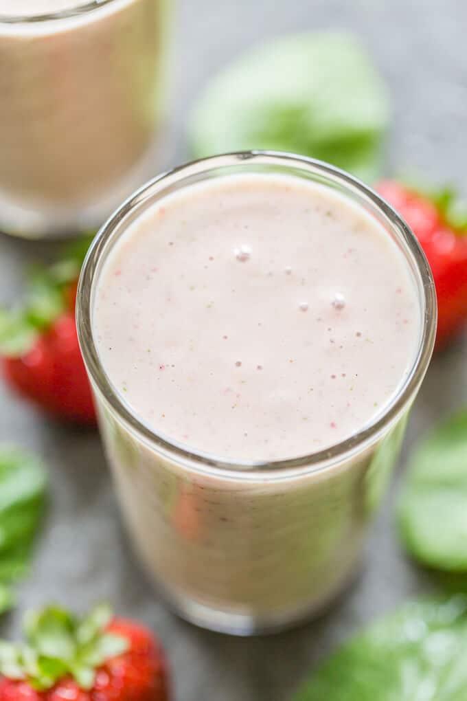 PBJ Spinach Banana Smoothie from overhead surrounded by strawberries and spinach