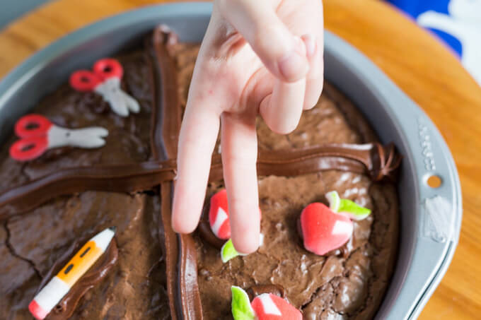 Child displaying two fingers over a pan of brownies