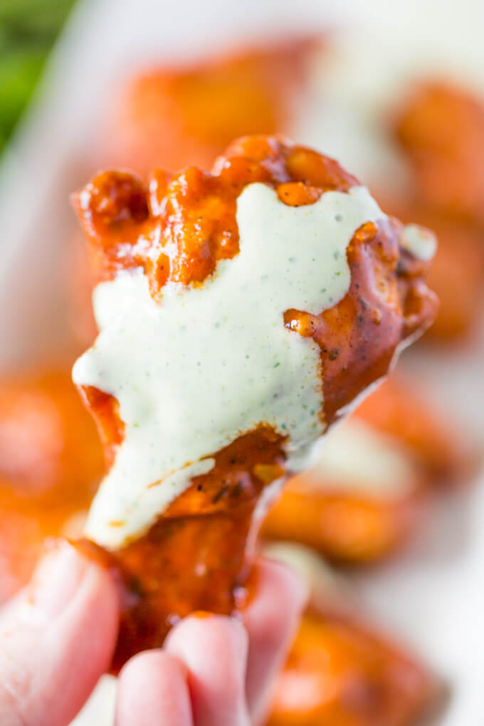 Taco Sauce Buffalo Wing with Cilantro Sour Cream Drizzle in a woman's hand