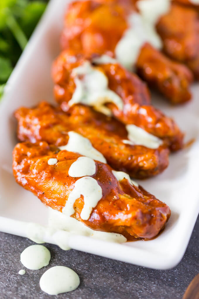Taco sauce Buffalo Wings with Cilantro Sour Cream Drizzle on a white plate
