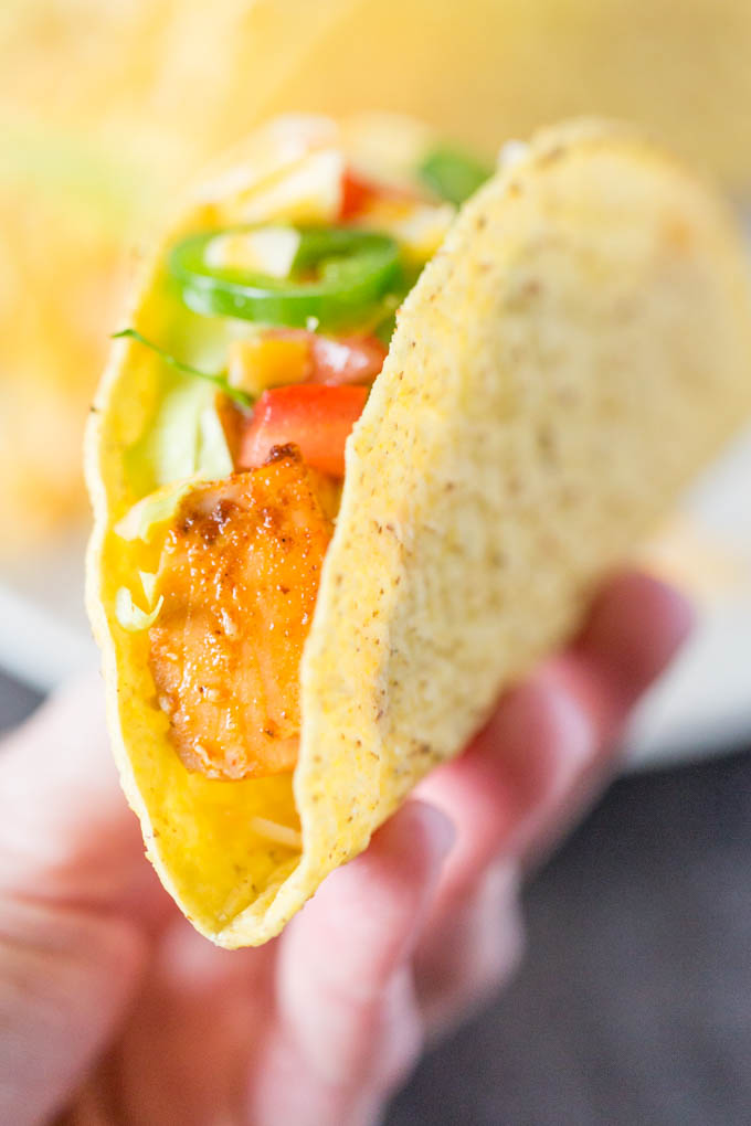 One crunchy salmon taco held in a woman's hand