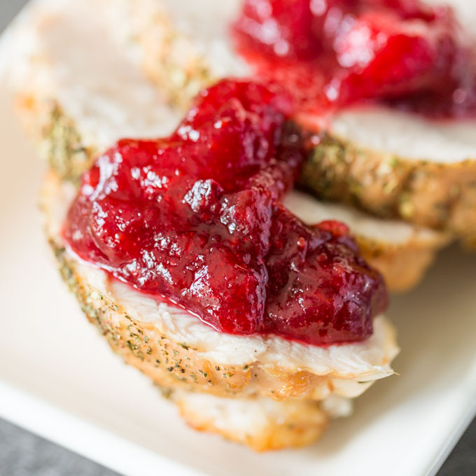 Turkey slices on a white plate with homemade cranberry sauce on top