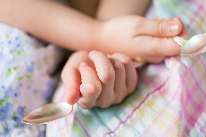 Two girls holding silver spoons