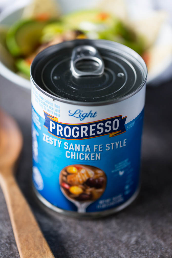Blue can of Progresso Light Zesty Santa Fe Soup with white bowl of soup and wooden spoon