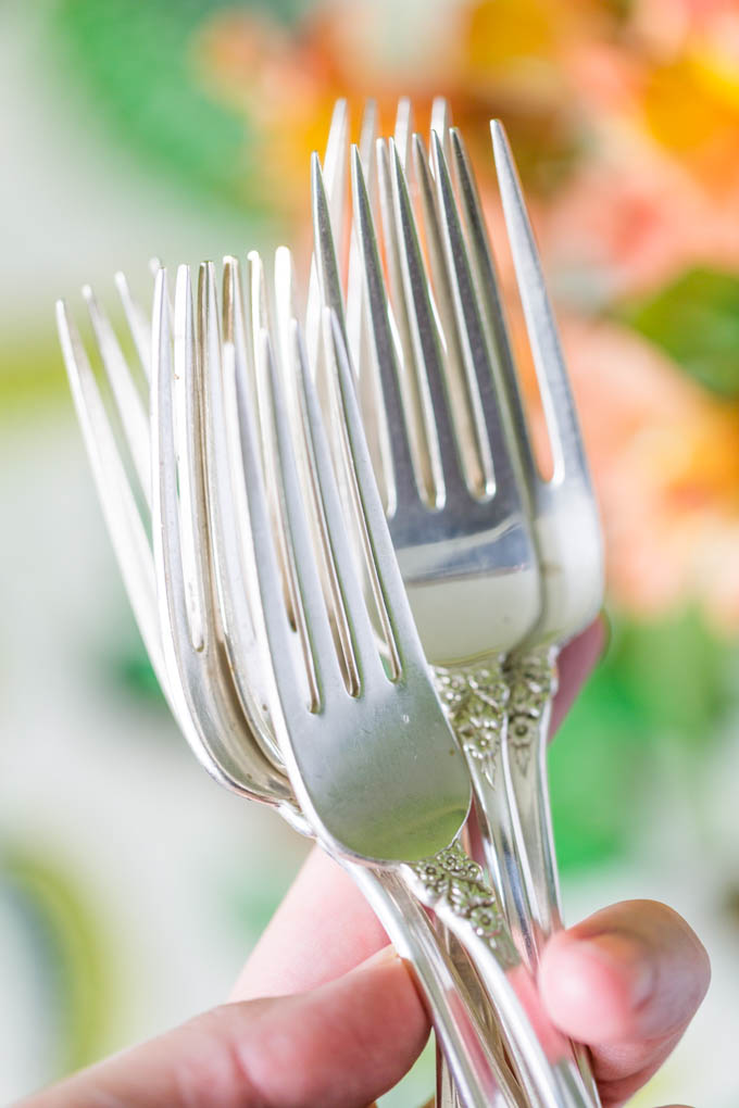 Silver flatware being held near alstroemerias