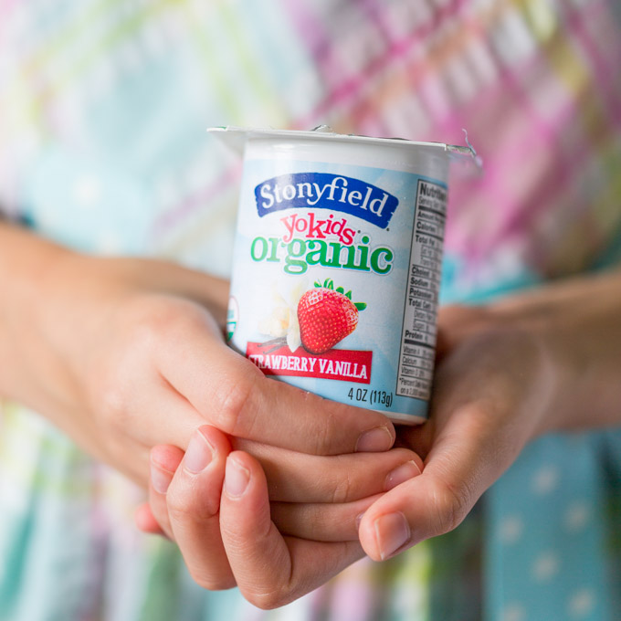 A girl's hands holding a yogurt cup