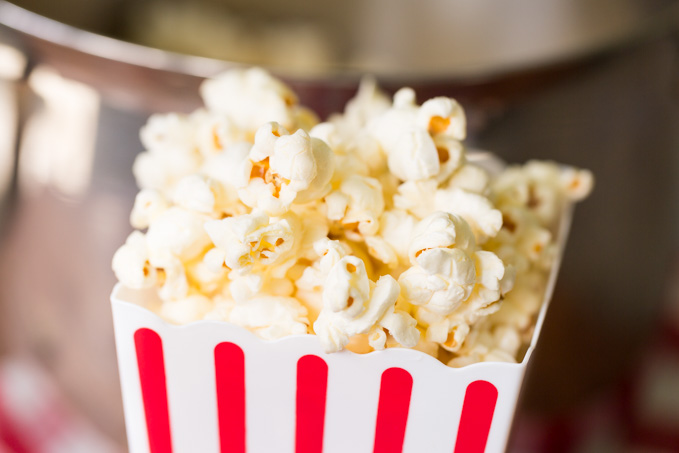 Closeup of movie theater popcorn in a red and white striped popcorn bucket