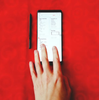 One hand on a Samsung Galaxy Note 8 with pen on Target shopping bag