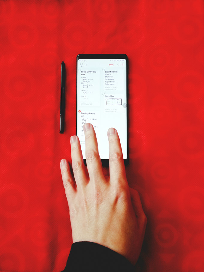 One hand on a Samsung Galaxy Note 8 with pen on Target shopping bag