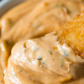Fish fillet dipping in remoulade sauce