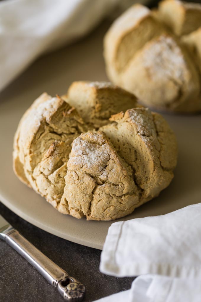 Two round loaves of gluten free irish soda bread on a baking stone