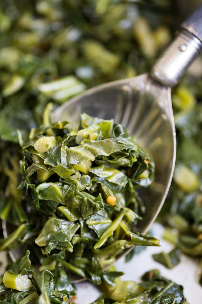 Antique serving spoon in a pan of cooked collard greens