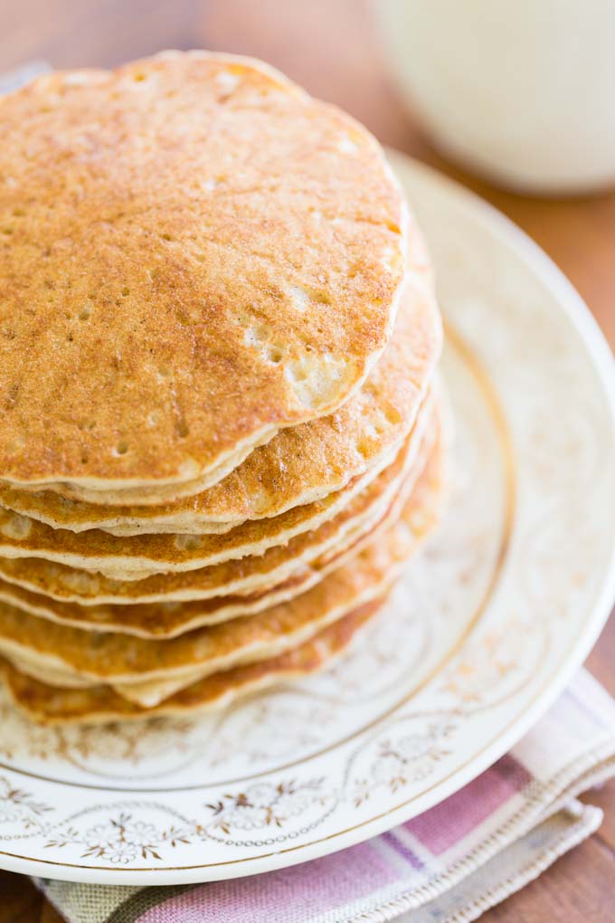 Sorghum pancakes on a white and gold plate on a plaid napkin