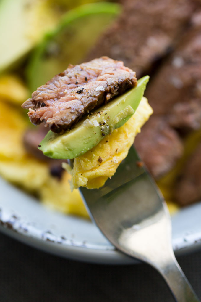 Flank Steak with avocado and scrambled eggs on a stainless steel fork