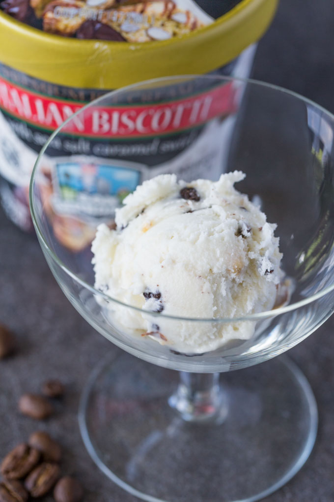 Scoop of ice cream in a clear glass surrounded by coffee beans