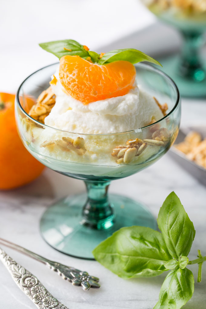 Greek yogurt in a glass with granola, honey, mandarin orange, and basil