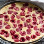 Raspberry clafoutis in a glass pie pan on a rack