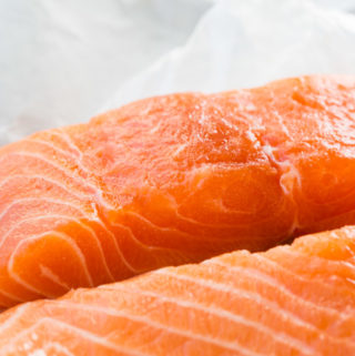 Raw salmon fillets on white paper