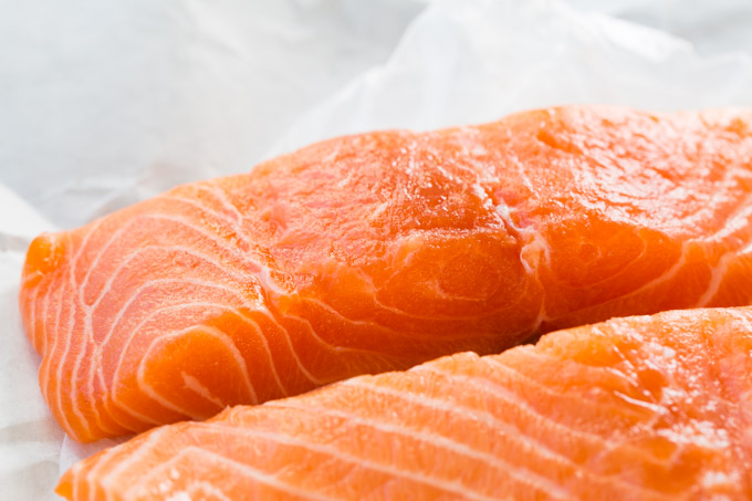 Raw salmon fillets on white paper