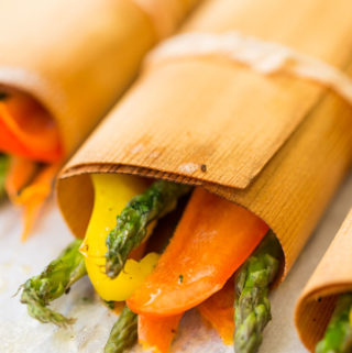 Asparagus, bell peppers, and carrot slices in cedar wraps tied with string