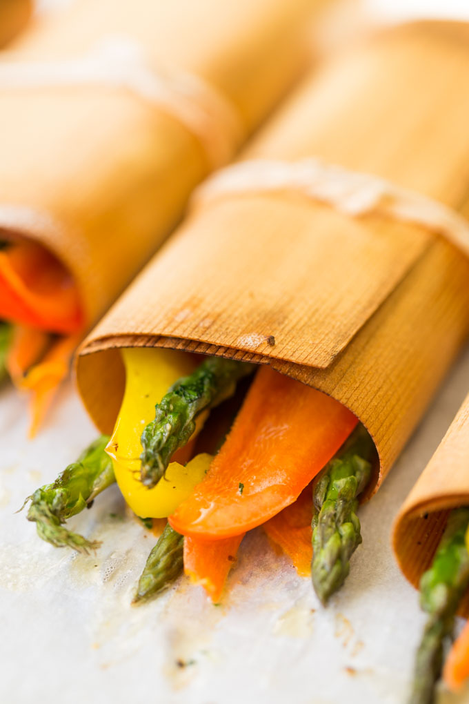 Asparagus, bell peppers, and carrot slices in cedar wraps tied with string