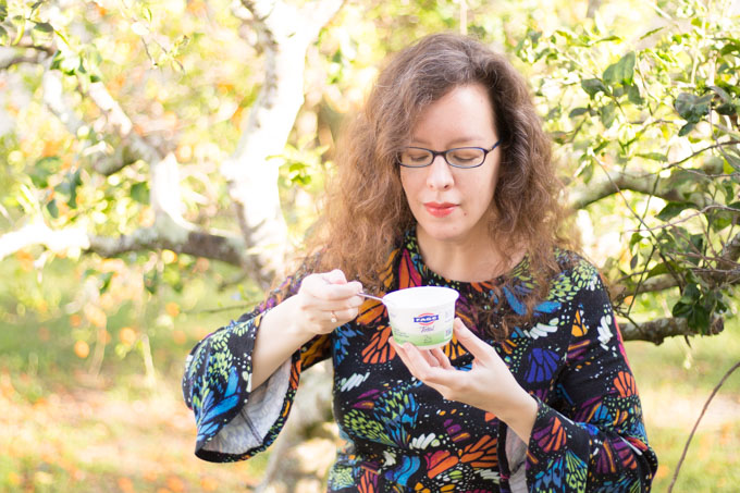 Woman eating FAGE Total Greek Yogurt with a spoon outside