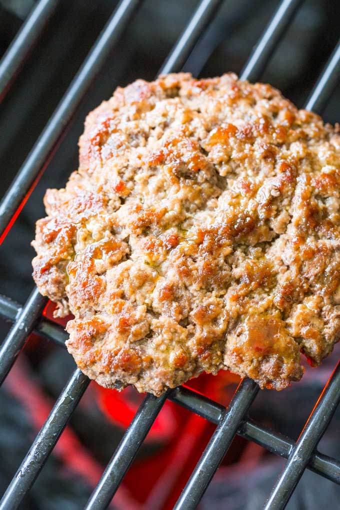 Grilling bison burgers on a lit charcoal grill