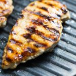 Yogurt marinated chicken breast cooking in a nonstick grill pan with grill marks