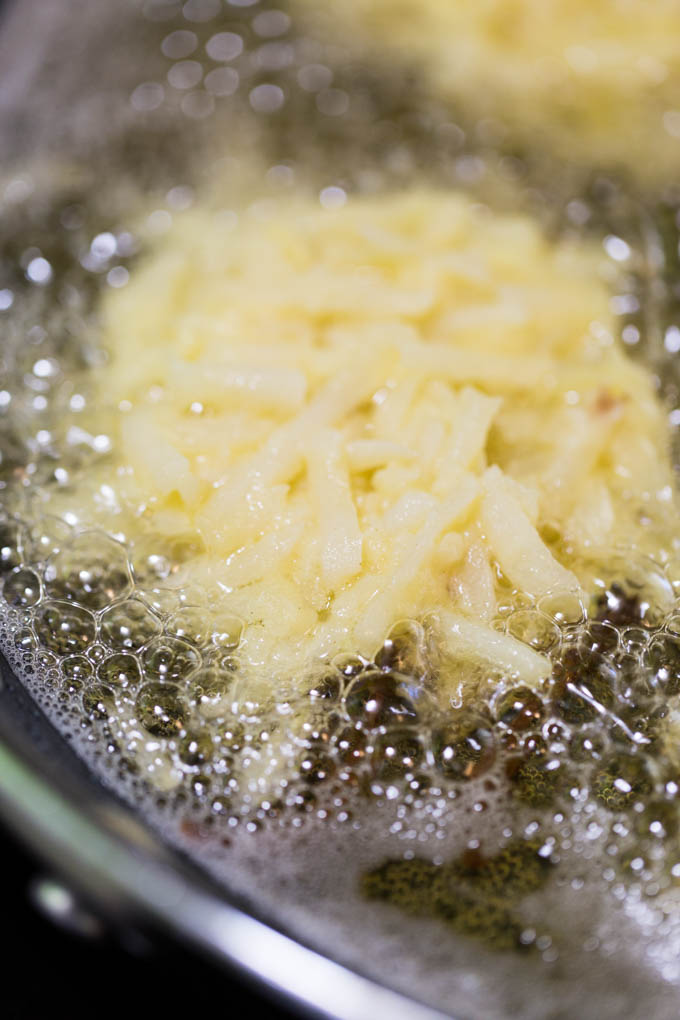 Potato latkes shallow frying in a skillet