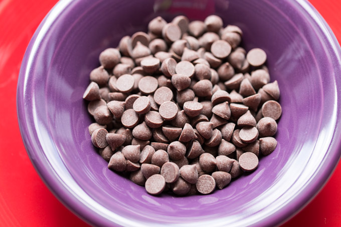 Chocolate chips in a purple bowl on a red plate