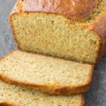 Large loaf from a paleo bread recipe with two slices cut on a gray countertop