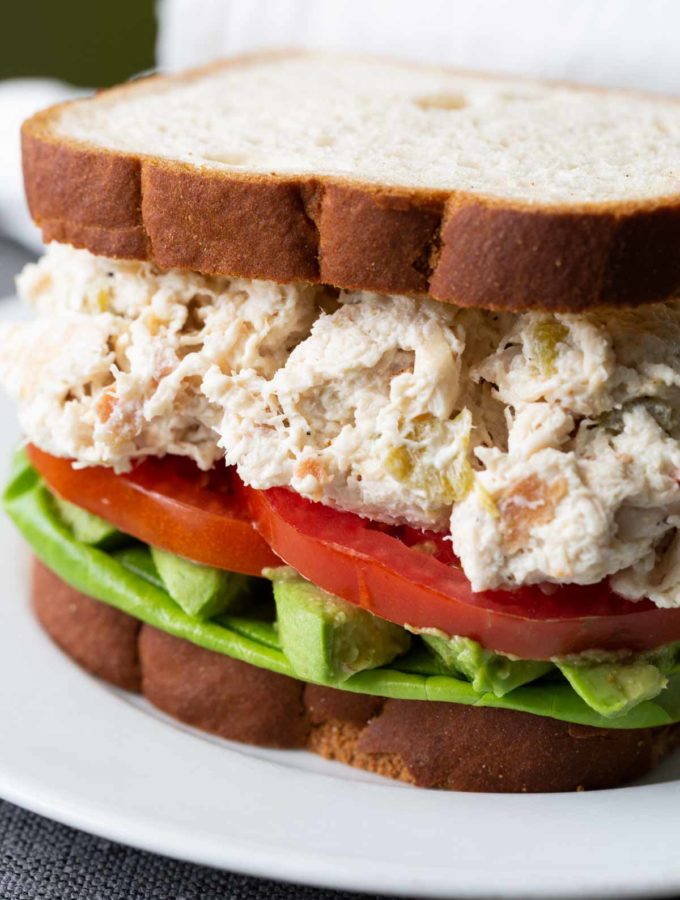 Green chile chicken salad sandwich on a white plate
