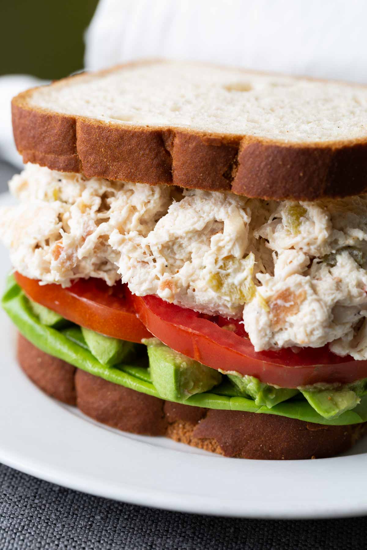 Green chile chicken salad sandwich on a white plate