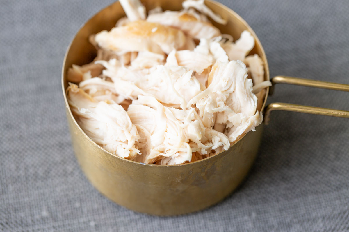 Shredded chicken in a gold measuring cup