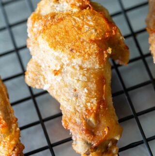 Crispy baked chicken wing on a rack showing how long to cook chicken wings in the oven