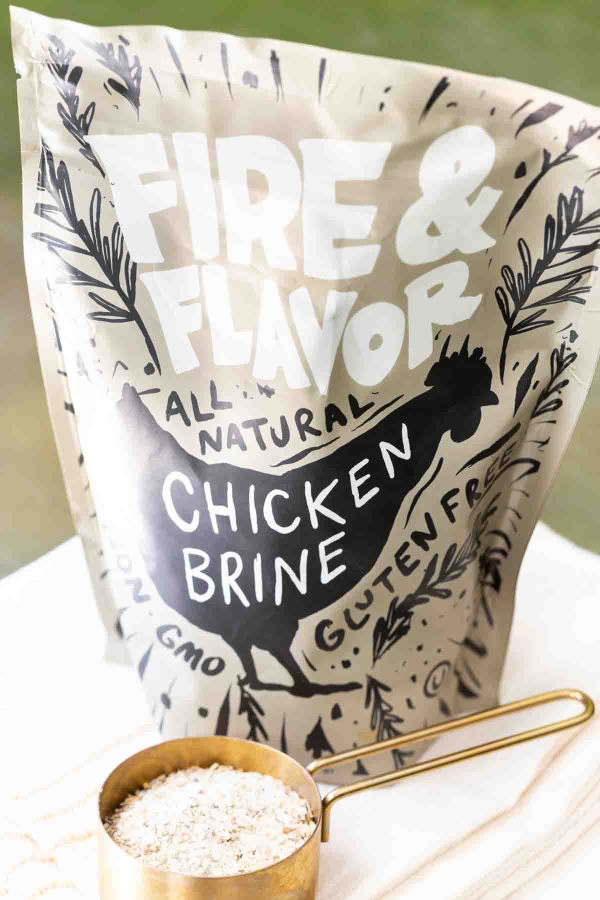 A measuring cup of chicken brine mix next to the package of Fire and Flavor Chicken Brine
